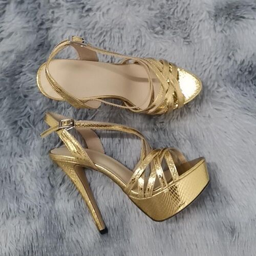 Goldene Stiletto-Plateauschuhe auf grauem, pelzigem Untergrund.