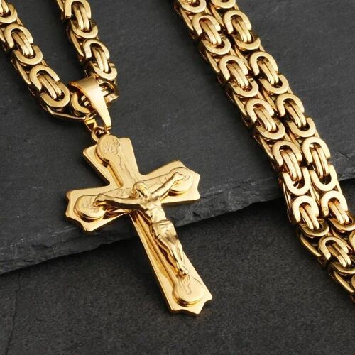 Goldene Kette mit Kreuzanhänger auf grauer Steinoberfläche. Goldene Kette mit Kreuzanhänger auf grauer Steinoberfläche.