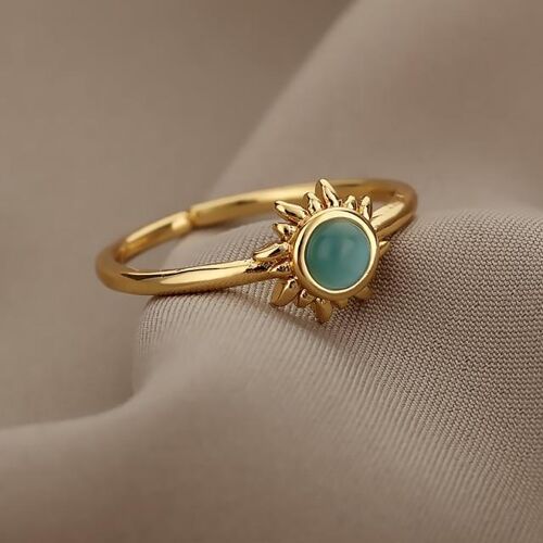 Goldener Ring mit türkisfarbenem Stein auf beigem Stoff präsentiert. Goldener Ring mit türkisfarbenem Stein auf beigem Stoff präsentiert.