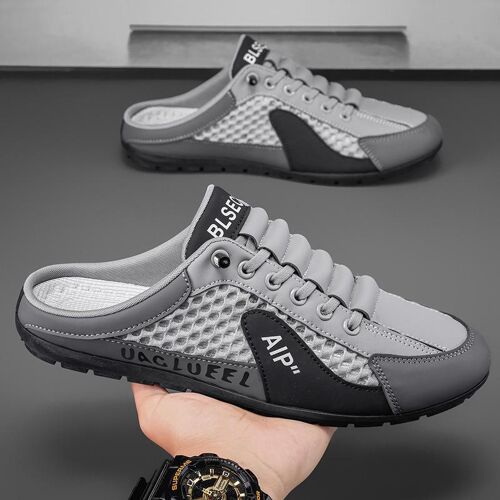 Hand hält graue, sportliche Mules mit Leder- und Netzdetails. Hand hält graue, sportliche Mules mit Leder- und Netzdetails.