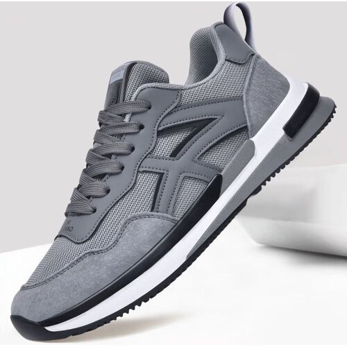 Grauer Sneaker mit schwarzen Akzenten, schwebend vor neutralem Hintergrund.