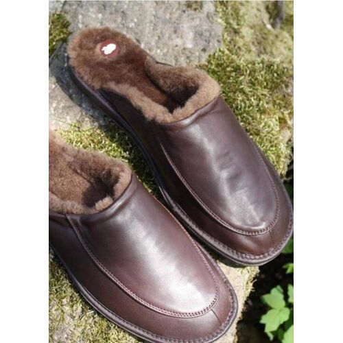 Braune Lederschuhe mit warmer Fellfüllung auf moosbedecktem Stein. Braune Lederschuhe mit warmer Fellfüllung auf moosbedecktem Stein.