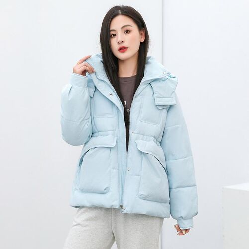 Person trägt hellblaue, wattierte Jacke in schlichtem, minimalistischem Raum.