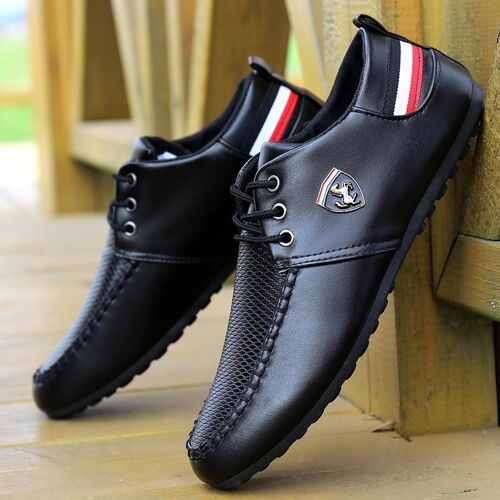 Schwarze Lederschuhe mit Emblem und Streifen auf Holzboden.