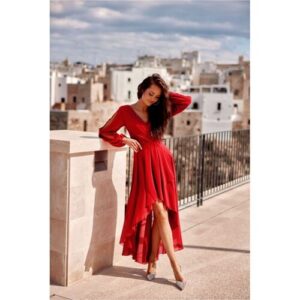 Person in rotem Kleid auf Terrasse mit Stadtlandschaft im Hintergrund.