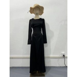 Schaufensterpuppe trägt ein langes schwarzes Kleid und Strohhut, steht vor weißer Wand.