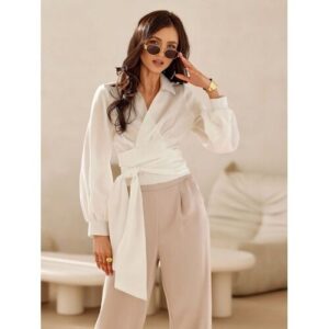 Frau in weißer Bluse und beiger Hose trägt Sonnenbrille.