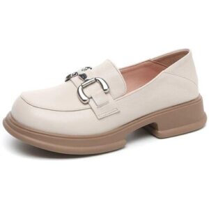 Beige Loafer mit silberner Schnalle und braunem Blockabsatz vor weißem Hintergrund.