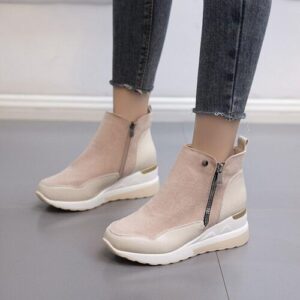 Hellbraune Stiefeletten mit Reißverschluss, getragen zu dunklen Jeans auf grauem Boden.