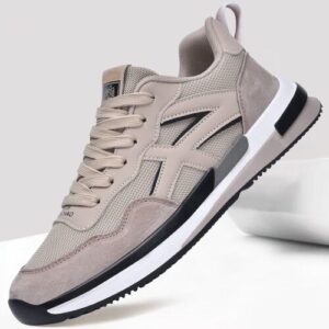 Beiger Sneaker mit schwarzer und weißer Sohle auf grauem Hintergrund.