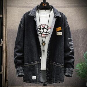 Schwarze Jeansjacke über weißem T-Shirt mit schwarzem Aufdruck und Halskette.