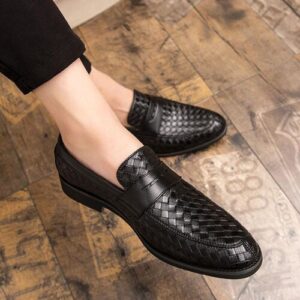 Schwarze gewebte Lederschuhe auf einem Holzboden, elegante Herrenschuhmode.