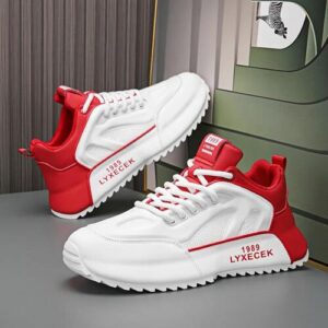 Rot-weiße Sneaker auf grauem Untergrund vor einer gestreiften Wand.