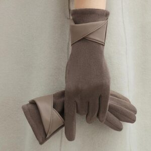 Zwei braune Handschuhe mit Lederdetails auf beigem Hintergrund.