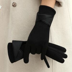 Schwarze Handschuhe mit Lederdetails auf beigem Mantelhintergrund.