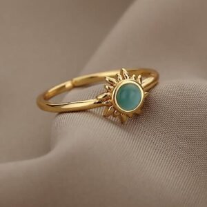Goldener Ring mit türkisfarbenem Stein auf beigem Stoff präsentiert.