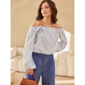 Frau in Off-Shoulder-Bluse und blauer Hose mit Handtasche.