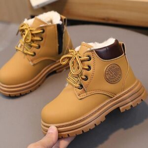 Paar braune Schnürstiefel mit Fellfutter auf grauer Fläche.
