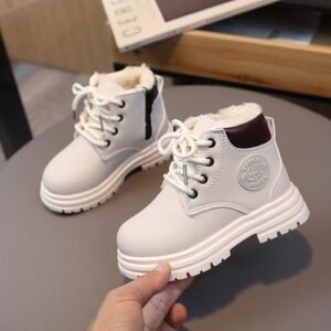 Weiße Kinderstiefel mit Schnürsenkeln und Fellfutter auf einem Tisch.