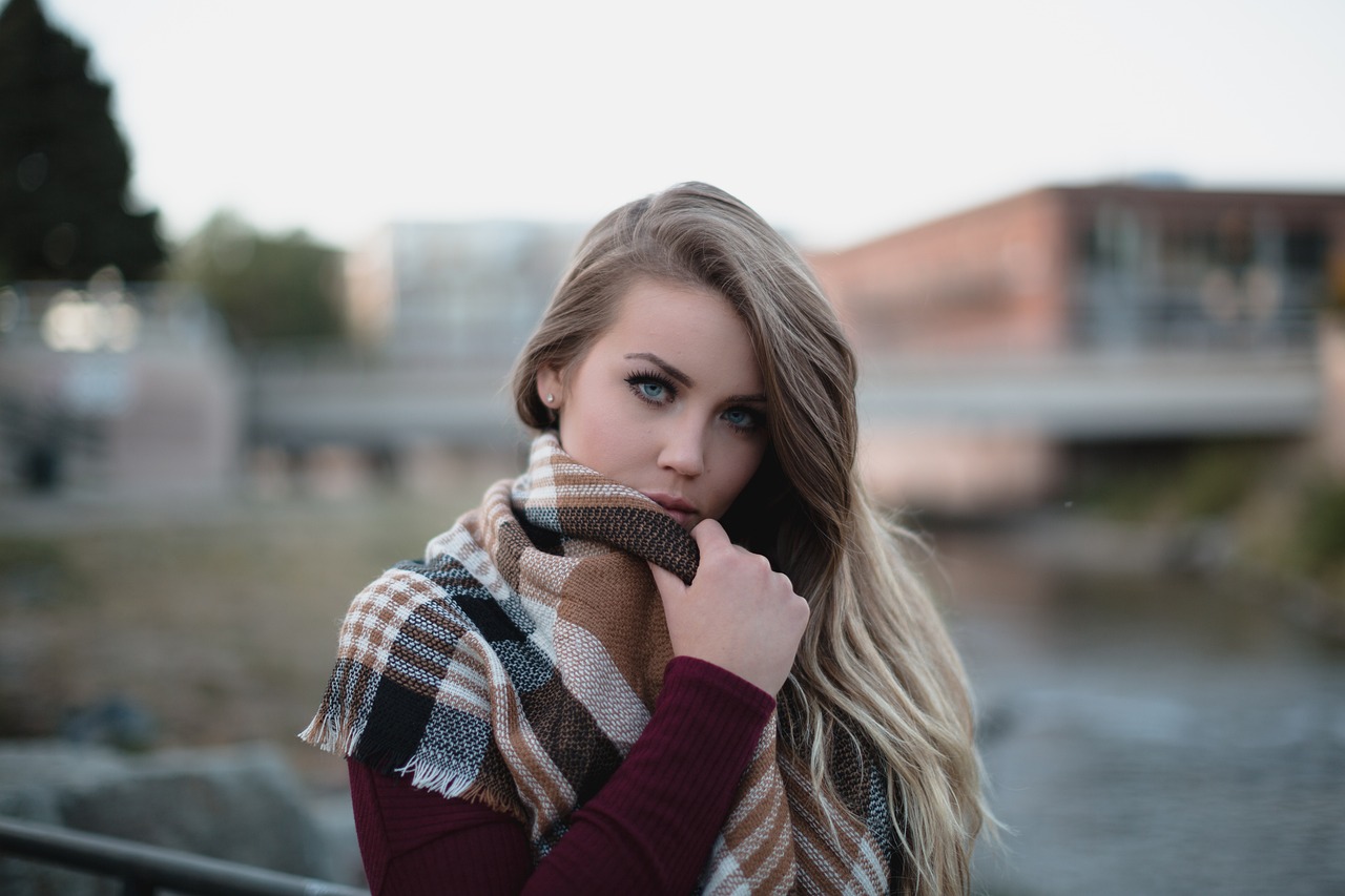 Person mit kariertem Schal am Flussufer stehend, im Freien.