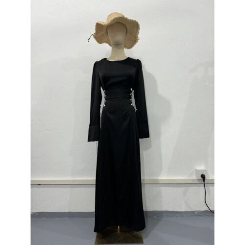 Schaufensterpuppe trägt ein langes schwarzes Kleid und Strohhut, steht vor weißer Wand.