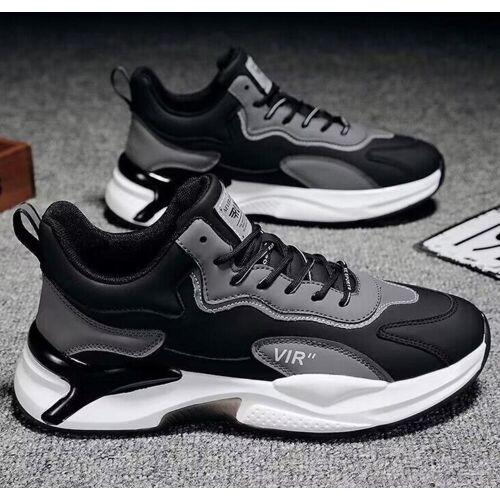 Schwarze und graue Sneaker mit weißer Sohle auf grauem Teppichboden.